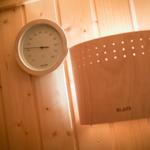 Sauna with wooden wall, thermometer, and heater.