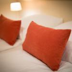 Headboard with two orange pillows and a bedside lamp.