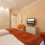Bedroom with bed, wardrobe, TV and armchair.