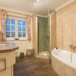 Bathroom with shower, bathtub, and window with curtains.
