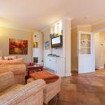Living room with sofa, TV, and wood stove. Terracotta floor and light walls.