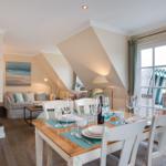 Dining area with table and chairs. Passage to living room with sofa and wall art.