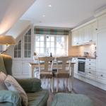 Dining area with kitchenette and seating under a sloped ceiling.