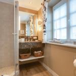 Bathroom with shower, sink, and window with blinds.
