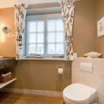 Bathroom with sink, toilet, and window with blinds.