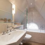 Bathroom with sink, mirror, bathtub, and shower under sloped ceilings.