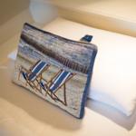 Pillow with beach motif on bed with white linens