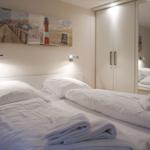 Zimmer mit Doppelbett, Wandbild und Spiegelschrank.