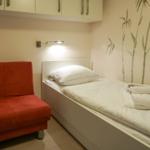 Schlafzimmer mit Bett, roter Sitzgelegenheit und Wanddekoration.