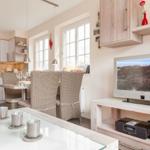 Küche mit Esstisch, Fernseher und Glasplatte.