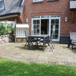 Terrace with table, chairs, and lounge chair in front of brick house