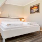 Bedroom with white bed, two nightstands, and wall picture.