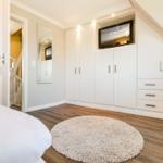 Bedroom with white closet, TV, and round rug.