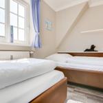 Room with two beds, window, and sloped ceiling.