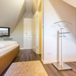 Bedroom with bed, TV, and coat rack.