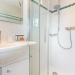 Badezimmer mit Dusche, Waschbecken und Spiegel