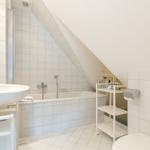 Badezimmer mit Badewanne, Waschbecken und Toilette unter Dachschrägen.