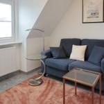 Ein Wohnzimmer mit Sofa, Tisch und Fenster unter Dachschräge.