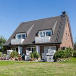 Haus mit Dachbodenfenstern und Terrasse im Garten.