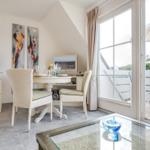 Esszimmer mit Tisch, Stühlen und Blick auf Balkon mit Sonnenschirm.