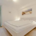 Bedroom with white bed, nightstand, and wall art.