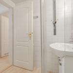 Bathroom with sink, mirror, and shower. Door leads to bedroom.