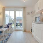 Living area with kitchen, bedroom and terrace. White furniture, blue cushions and rug.