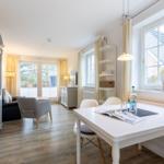 Wohn- und Essbereich mit Tisch, Stühlen und Fenstern.