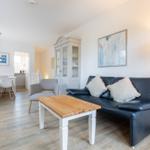 Wohn- und Essbereich mit Sofa, Tisch und Küchenbereich im Hintergrund.