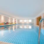 Innenpool mit farbiger Wandgestaltung und metallischer Treppe