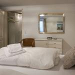 Schlafzimmer mit Bett, Kleiderschrank und Spiegel an der Wand.