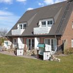 Rotes Backsteingebäude mit Balkon und Gartenbereich mit Liegestühlen.