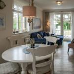 Esszimmer mit weißem Tisch und Stühlen. Wohnbereich mit Sofa und TV.