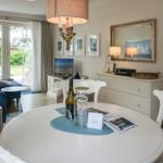 Rundtisch mit Stühlen, Fernseher und Fenster zum Garten.