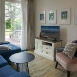 Wohnzimmer mit Sofa, Sessel, TV und Blick auf den Garten.