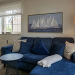 Blauer Sofa mit Kissen und Wandbild von Segelbooten.