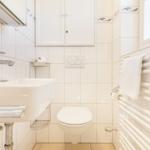 Badezimmer mit Waschbecken, Toilette und Handtuchhalter.