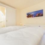 Schlafzimmer mit Doppelbett, Wandbild und Nachttisch mit Lampe.