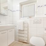 Badezimmer mit Waschbecken, Toilette und Dusche. Weiße Fliesen mit blauem Fisch-Muster.