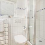 Badezimmer mit Dusche, Toilette und Heizung.