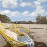 Terrasse mit zwei gelben Stühlen und Blick auf Bäume und Himmel.