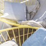 Gelber Hängesessel mit Kissen und Decken auf Terrasse.