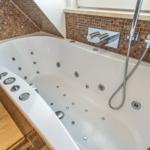 Whirlpool-Badewanne mit Dusche und Mosaikfliesen an der Wand