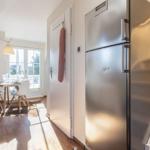 Küche mit Edelstahlkühlschrank, Tisch und Stühle im Hintergrund.