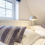 Zwei Betten mit Kissen und Nachttisch unter einem Fenster mit Blick nach draußen.