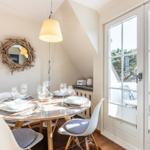 Runder Esstisch mit Stühlen und Fenster zur Terrasse.