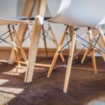 Moderne Stühle mit Holzbeinen stehen auf einem Fellteppich.