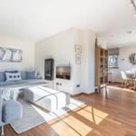 Wohn- und Essbereich mit Sofa, Fernseher und Holzboden.