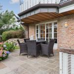 Terrace with seating area and flower bed in front of brick house