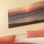 Bed with pillows under wall picture of sunset at beach